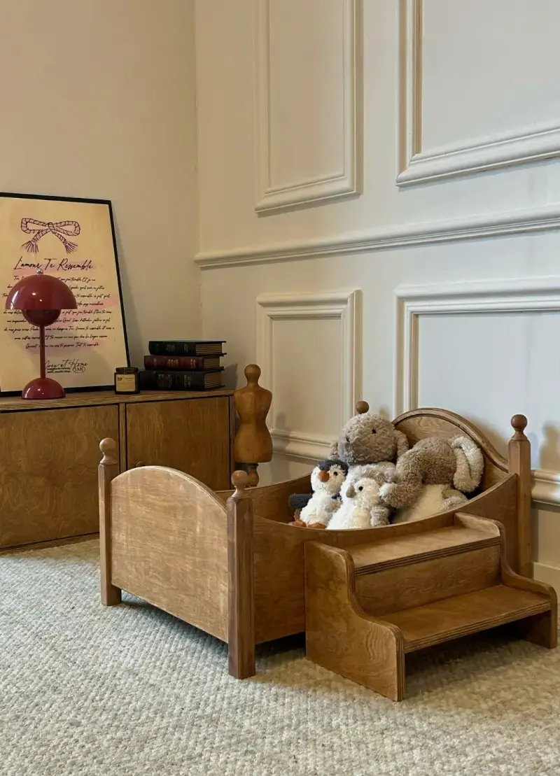 A small wooden pet bed styled with warm home decor